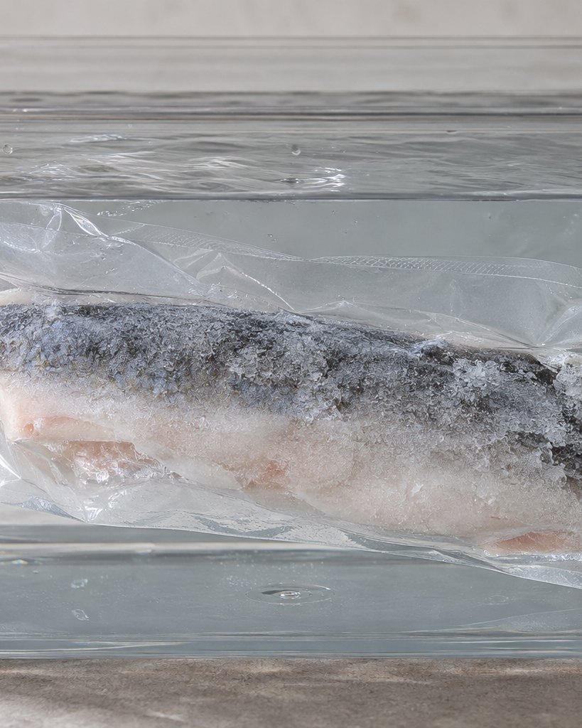 Peixe embalado em vácuo, mergulhado na salmoura dentro de um recipiente transparente