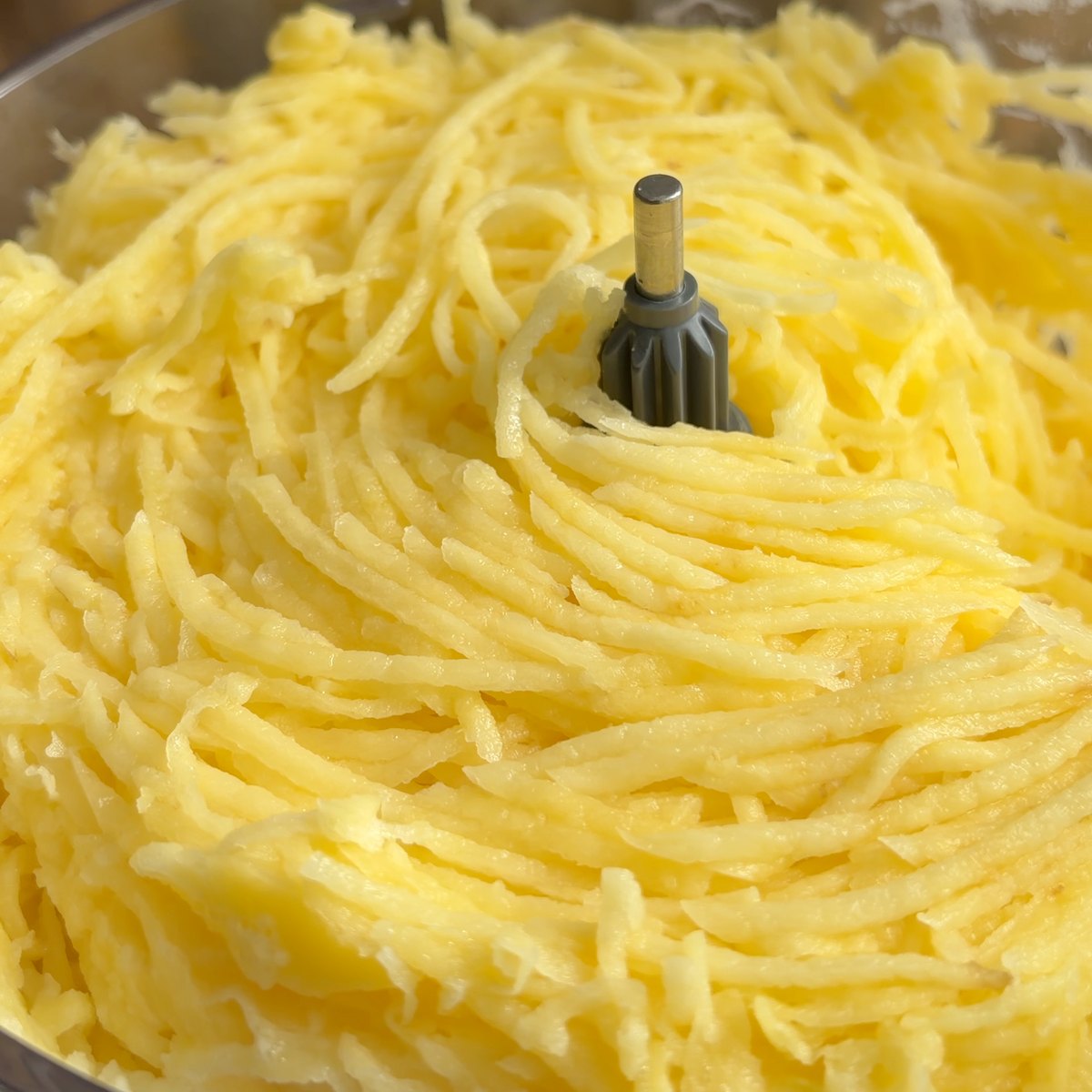 A batata ralada no copo do processador, em fios compridos e iguais