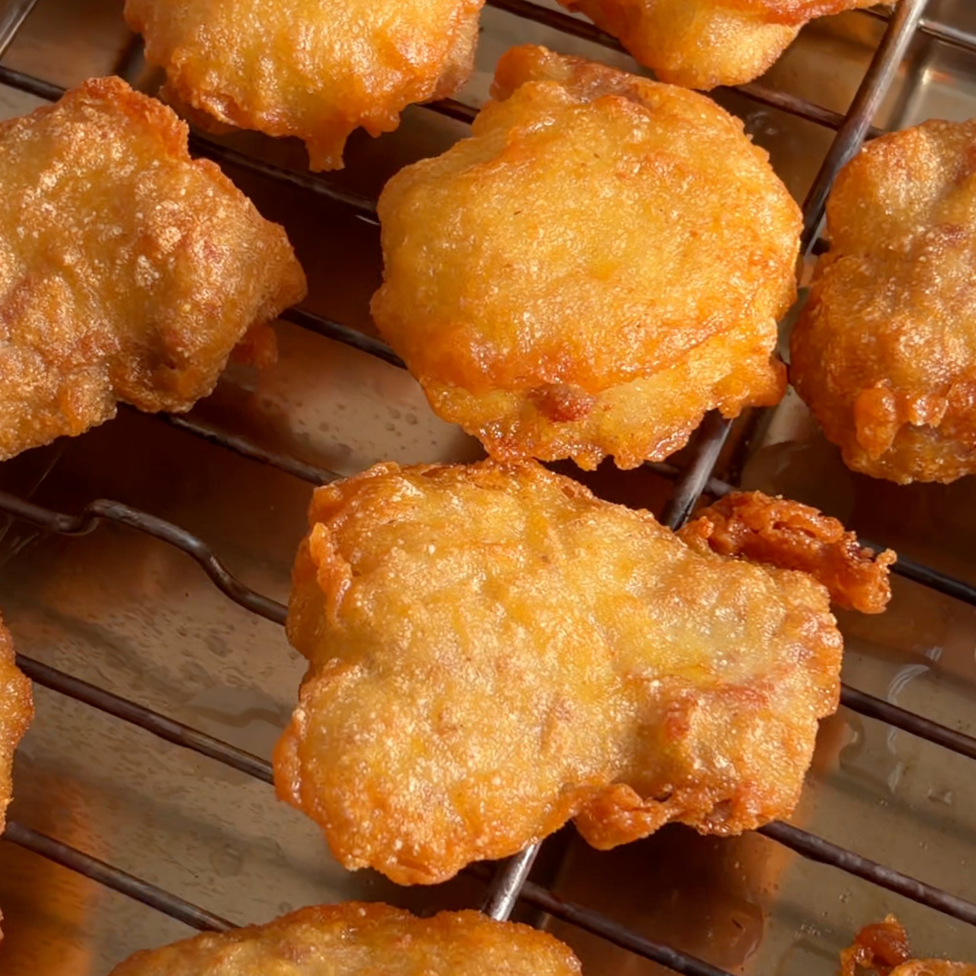 Nuggets de codorniz acabados de fritar, dourados, a arrefecer numa grelha